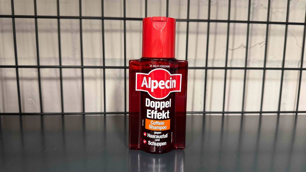 Eine Flasche Männer-Shampoo gegen Haarausfall steht zum testen in einem schwarzen Gitterregal.