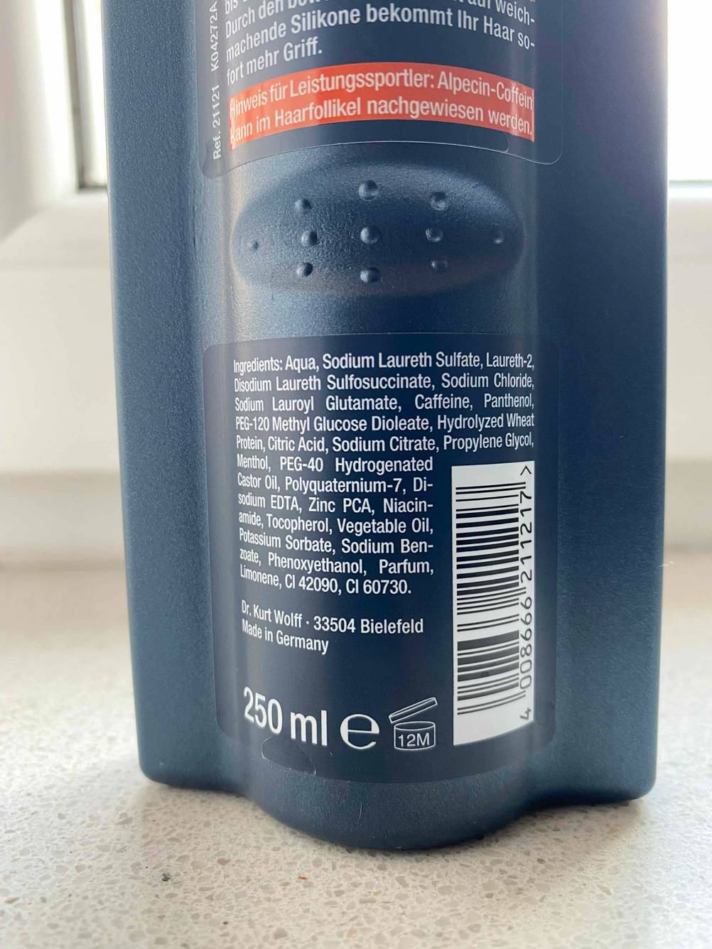 Nahaufnahme der Rückseite einer Flasche Alpecin-Shampoos mit Inhaltsangaben.