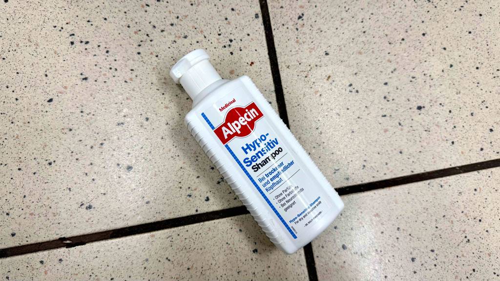 Eine Flasche getestetes Shampoo gegen trockene Kopfhaut liegt auf einem Fliesenboden.