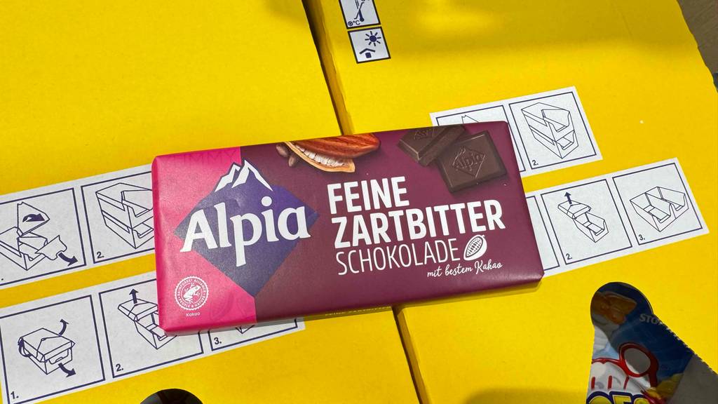 Alpia-Schokolade getestet: Eine Tafel liegt auf zwei Kartons mit anderen Süßigkeiten.