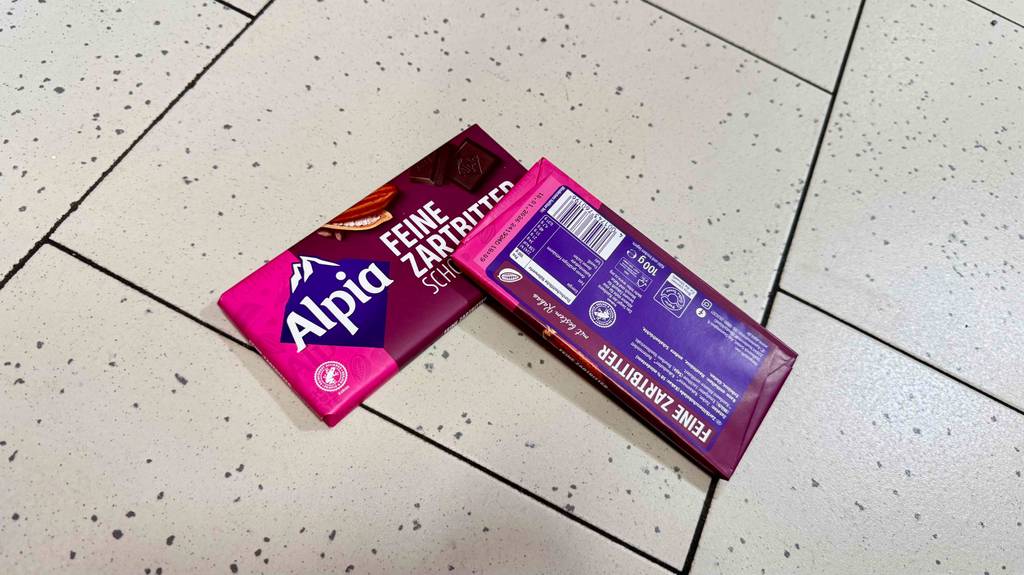 Alpia-Schokolade im Test: Eine Tafel liegt mit der Rückseite nach oben verkehrt und quer auf einer zweiten.