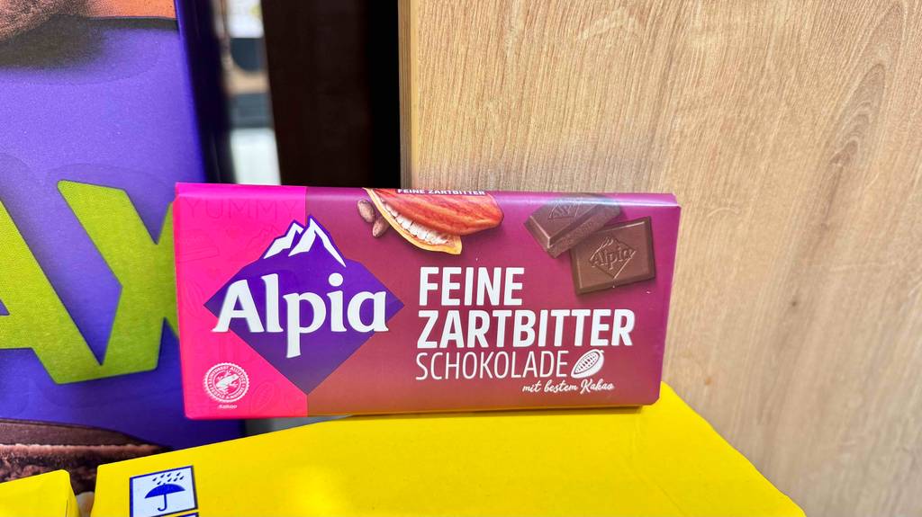 Alpia-Schokolade-Test: Eine Tafel der Sorte Feine Zartbitter lehnt an ein Holzregal.