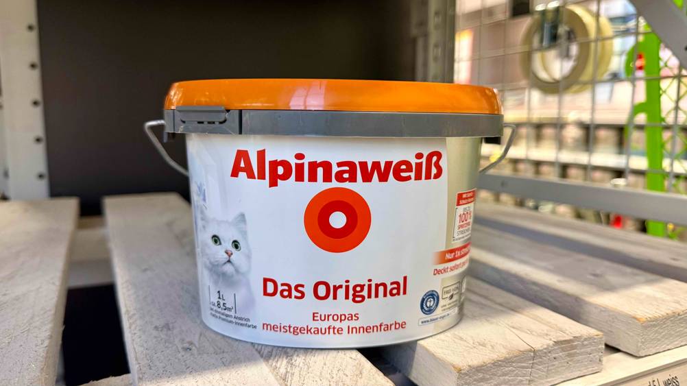 Alpina-Farbe im Test: Ein Eimer in einem Holzregal stehend.