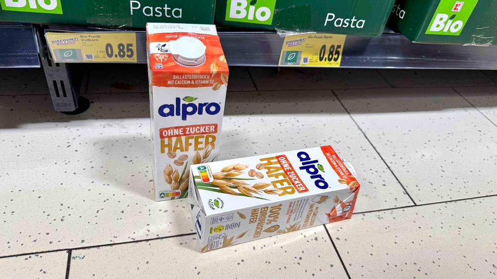 Vor einem Regal liegen und stehen zwei Packungen des Alpro-Haferdrinks im Test.