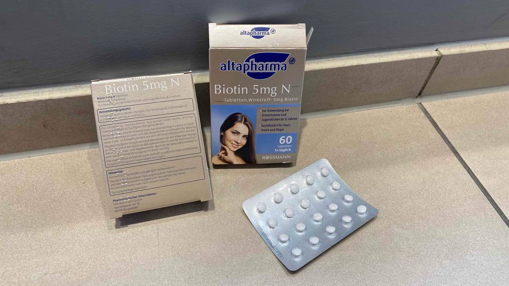 Biotin-Test: 60 Tabletten à 5 mg Biotin im Test befinden sich in einer Verpackung, die von vorn und eine zweite, die von hinten zu sehen ist. Davor liegt ein Blister.
