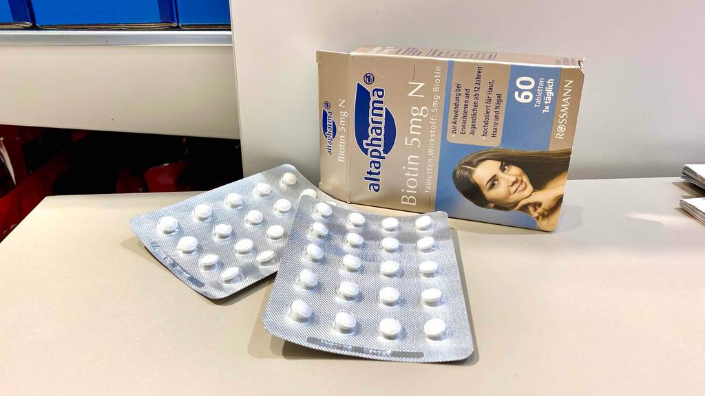 Tabletten à 5 mg Biotin im Test der Marke Altapharma Rossmann liegen im Blister neben der Verpackung auf einer hellen Oberfläche.