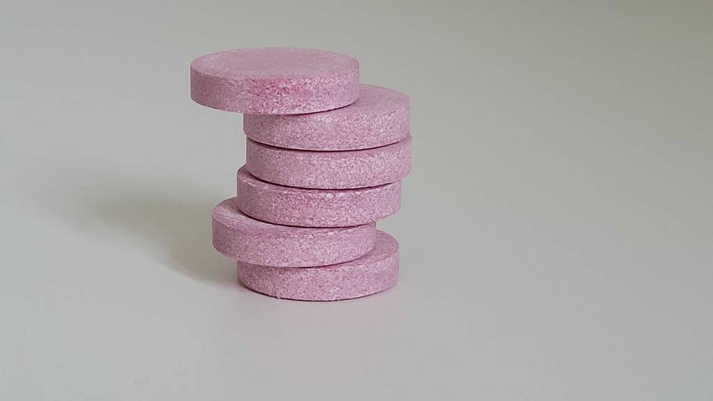 Ein Stapel getesteter Vitamin-C-+-Zink-Kapseln befindet sich auf einer weißen Oberfläche.