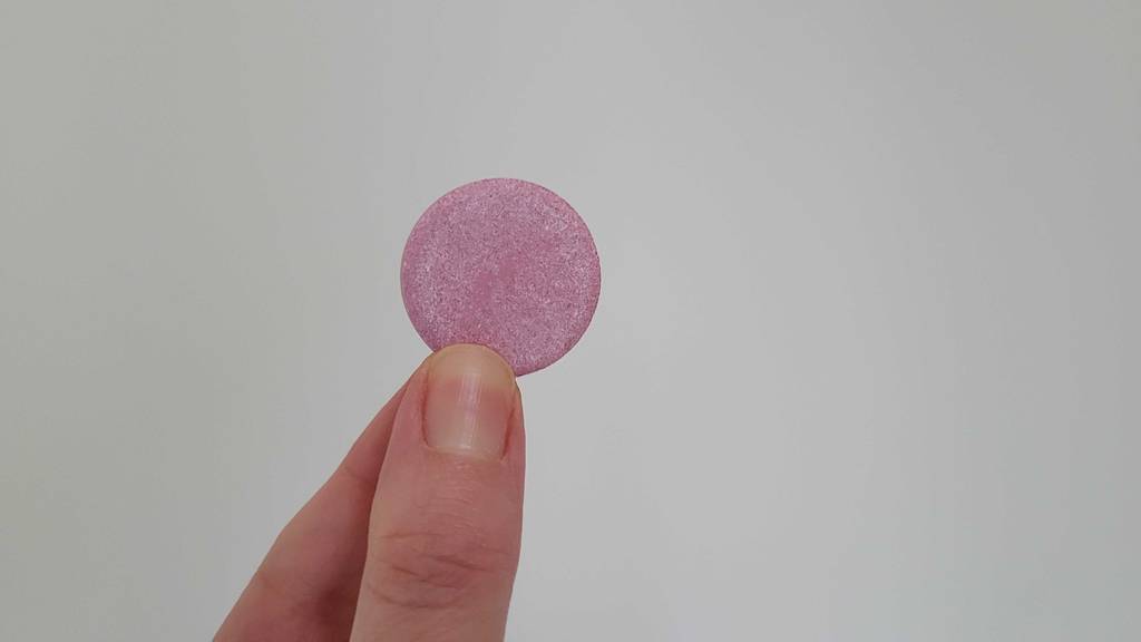 Zwischen zwei Fingern steckt eine getestete Vitamin-C-+-Zink-Kapsel.