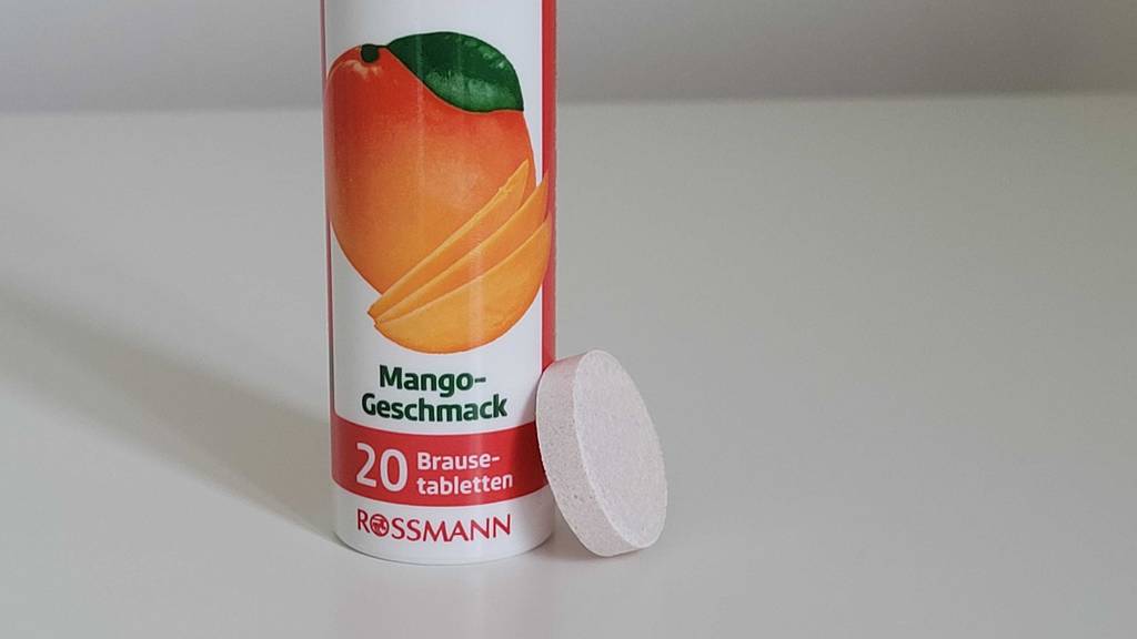 Nahaufnahme einer Dose mit Multivitamin-Brausetabletten im Test, an die sich eine Brausetablette lehnt.