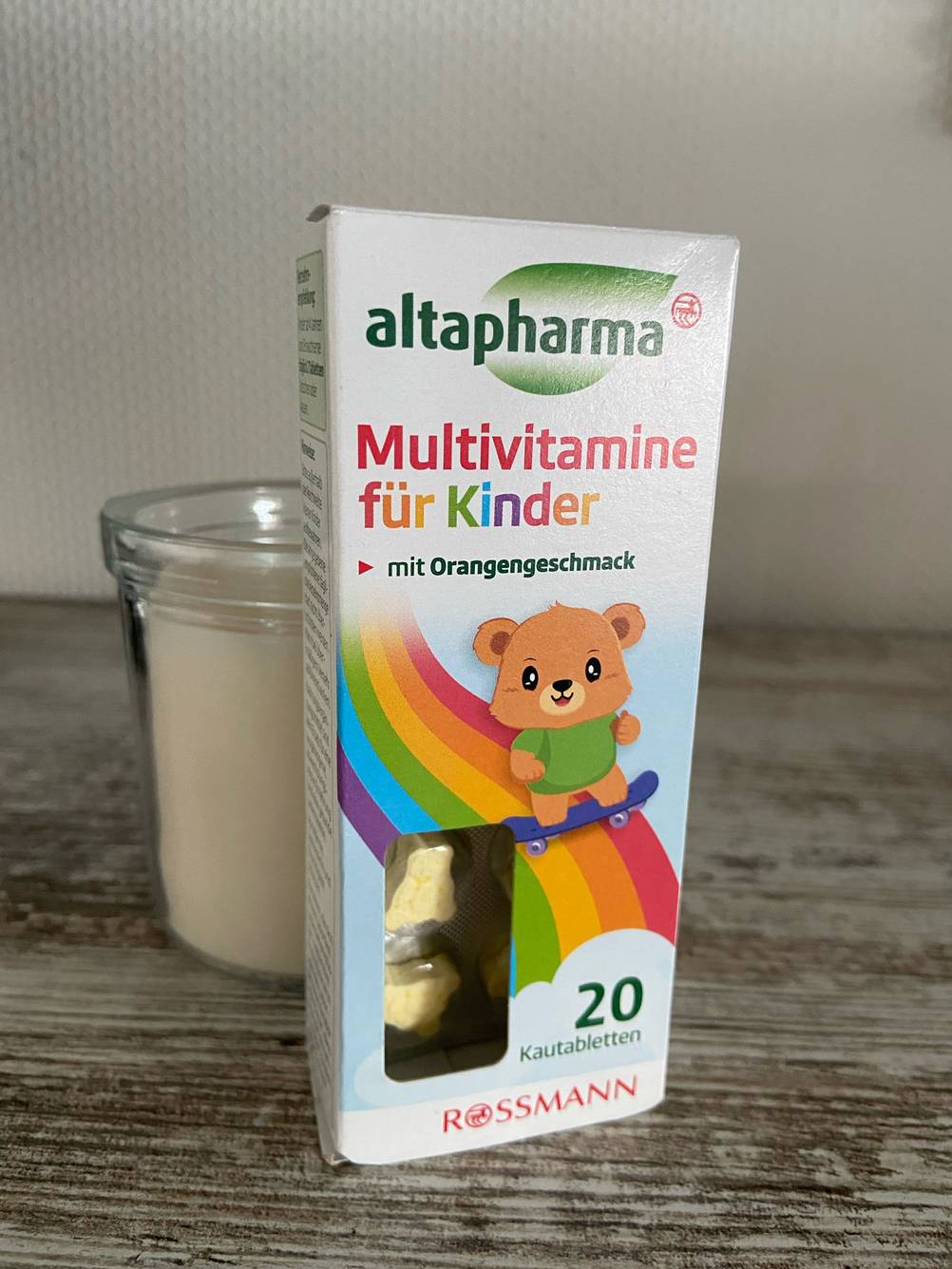 Die Verpackung von getestetem Multivitaminpräparat steht vor einem Glas.