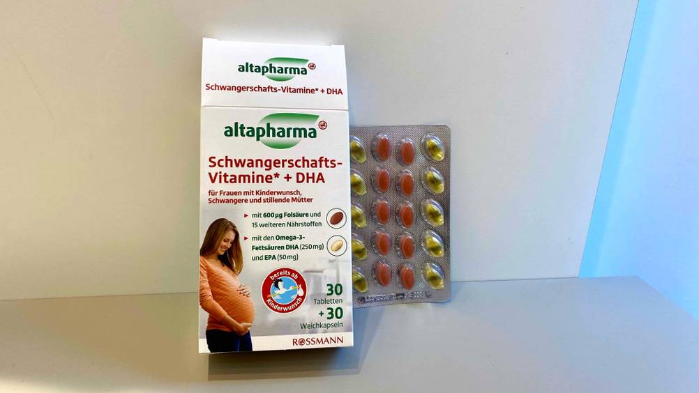 Eine Originalverpackung Schwangerschaftsvitamine im Test neben einem Tablettenblister vor einer hellen Fläche.