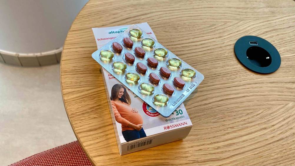 Schwangerschaftsvitamine getestet: Auf einem Holztisch liegt eine Originalverpackung mit einem Tablettenbister darauf.