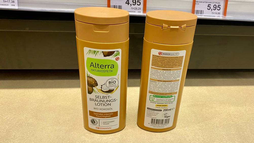 Selbstbräuner getestet: Zwei Flaschen stehen auf einem Boden vor einem Regal, einmal Vorderseite nach vorne, einmal Rückseite nach vorne.