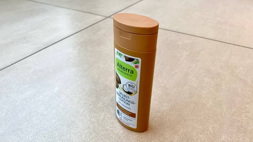 Im Test: Eine Flasche Selbstbräuner von schräg seitlich auf einem Fließenboden.