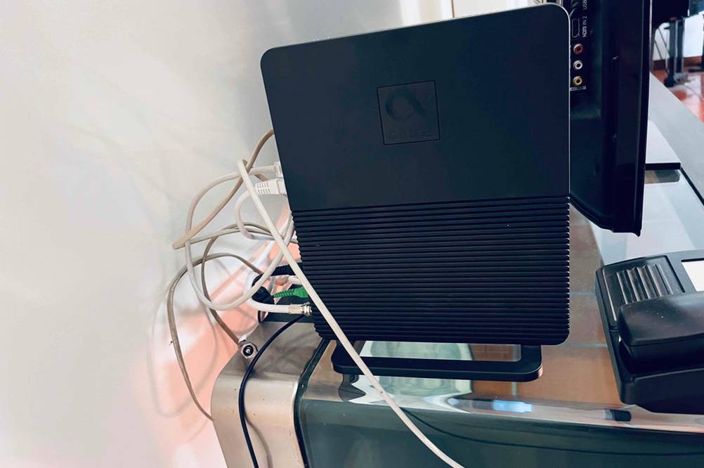 Glasfaser-Router-Test: Schwarzer Router steht senkrecht auf einem Büroschreibtisch mit Computer-Komponenten.