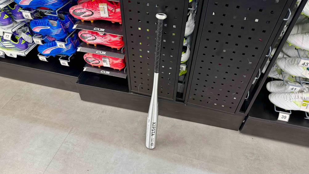 Vor einem Regal mit Produkten steht der Alu-Baseballschläger im Test auf dem Boden.