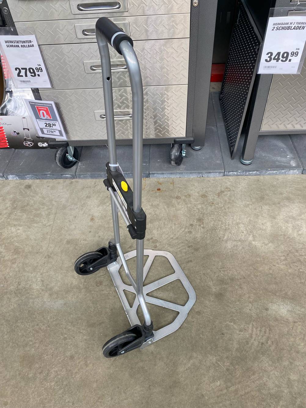 Eine Alu-Sackkarre im Test vor einem Metallregal auf einem Betonboden.