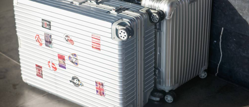 Aluminium-Koffer im Test: Aufnahme von verschiedenen Aluminium-Koffern mit Rollen, vorderes Modell mit Aufklebern versehen.