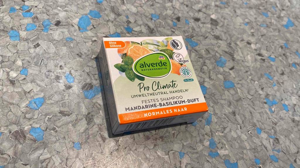 Haarseife Im Test: eine Packung Alverde Festes Shampoo liegt auf einem grau/blau gesprenkelten Untergrund.