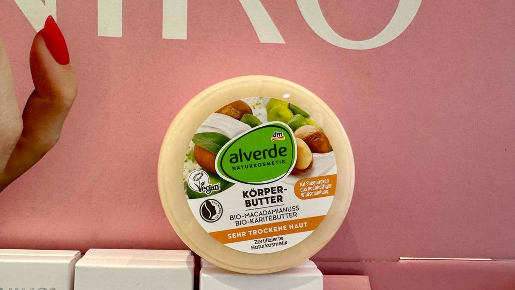 Eine Dose inklusive getesteter Körperbutter steht vor einem rosafarbenen Hintergrund.