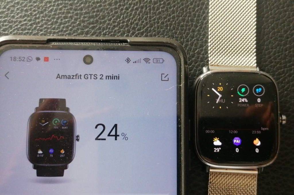 Auf schwarzen Hintergrund: Amazfit GTS 2 Mini EKG-Uhr im Test liegt neben einem Smartphone, auf dem die zur Uhr gehörige App zu sehen ist. Die Uhr verfügt über ein Edelstahl-Armband.