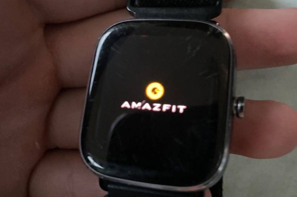Nahaufnahme einer Hand, die eine Amazfit GTS 2 Mini EKG-Uhr im Test hält, die über ein schwarzes Stoff-Armband verfügt.