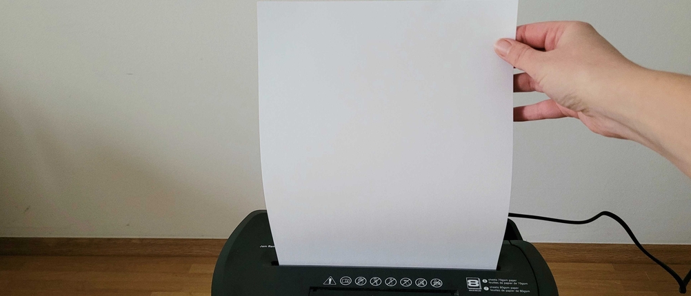 Aktenvernichter getestet: Eine Hand hält ein Papier, das in den Aktenvernichter eingeführt wird.