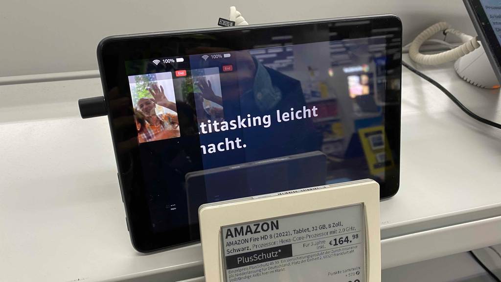 8-Zoll-Tablet-Test: ein eingeschaltetes Amazon Modell mit glänzendem Bildschirm ist inklusive Produktbeschreibung und Preis auf einem weißen Ausstellungstisch platziert.