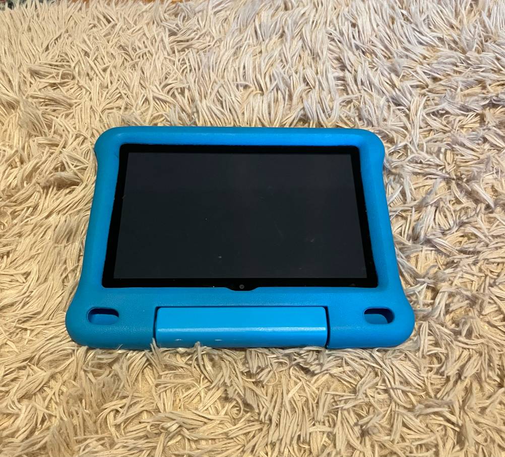Ein getestetes Kinder-Tablet mit einer blauen Hülle auf einem Teppich liegend.