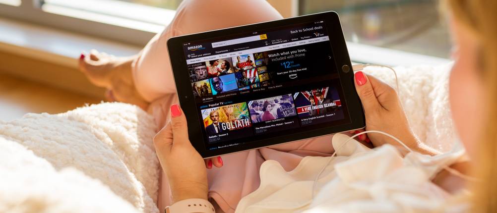 eine Frau schaut auf ein Tablet mit Startseite von Amazon Prime Video