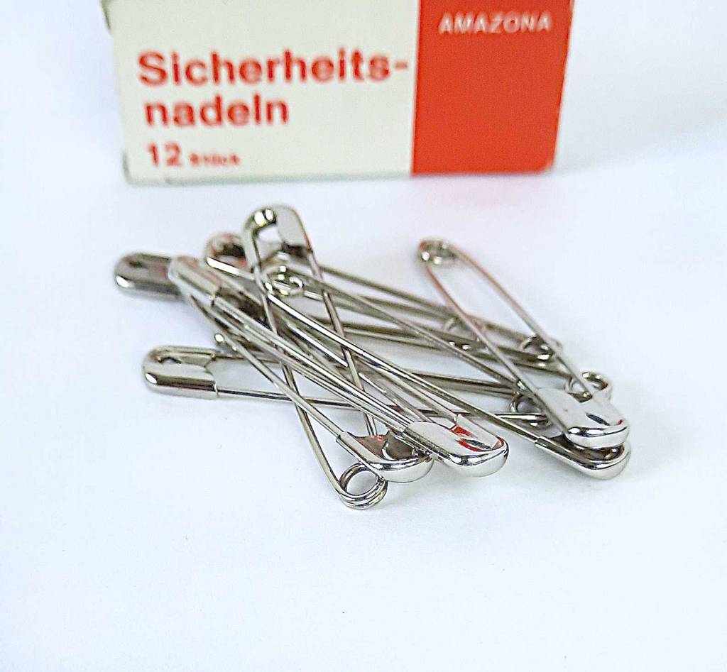 Detailansicht von Sicherheitsnadeln, die getestet vor der Verpackung liegen.