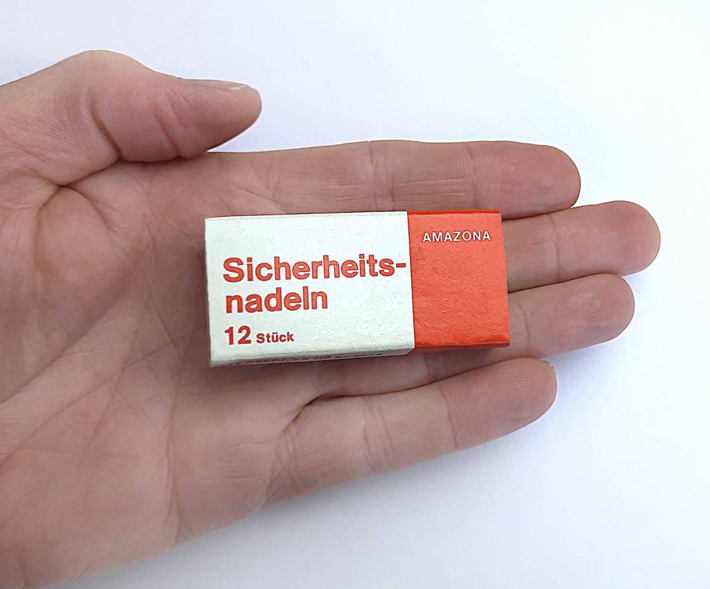 Die Verpackung von getesteten Sicherheitsnadeln liegt auf einer Handfläche.