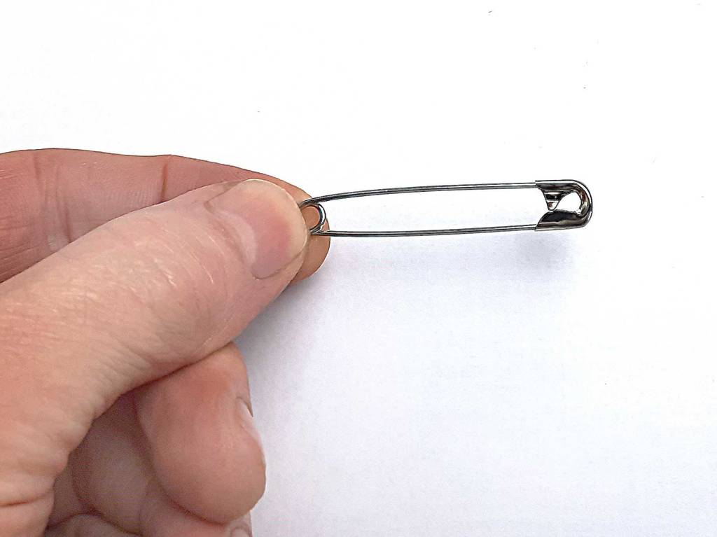 Im Test: Zwei Finger halten eine geschlossene Sicherheitsnadel.
