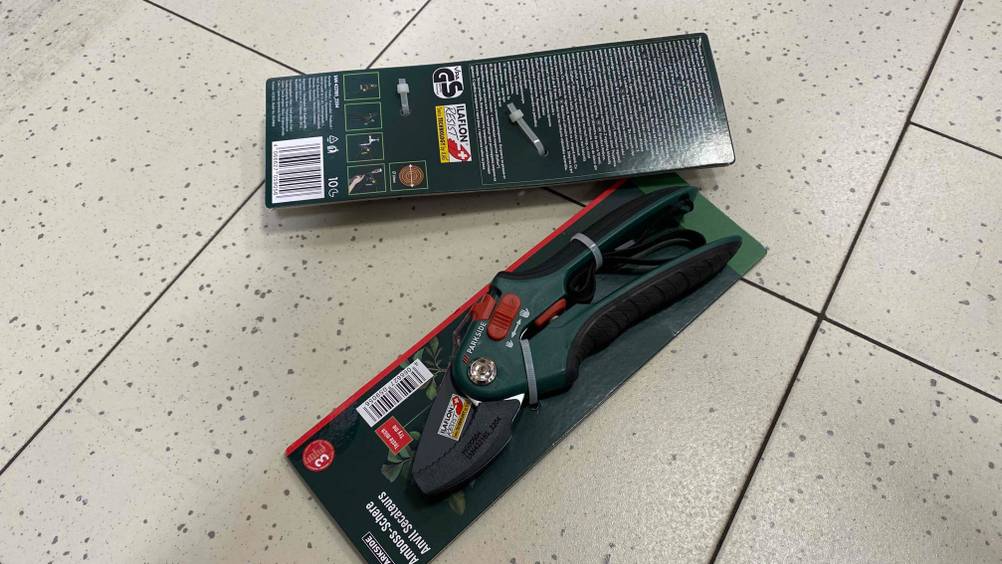 Auf dem Boden liegen zwei getestete Amboss-Gartenscheren verpackt auf dem Boden. 