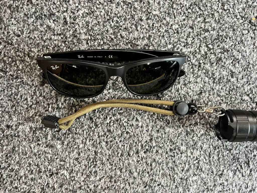 Taschenlampe 10000 Lumen im Test: Ansicht der Handhalteschnur, hinter der eine Sonnenbrille liegt zum Längenvergleich.