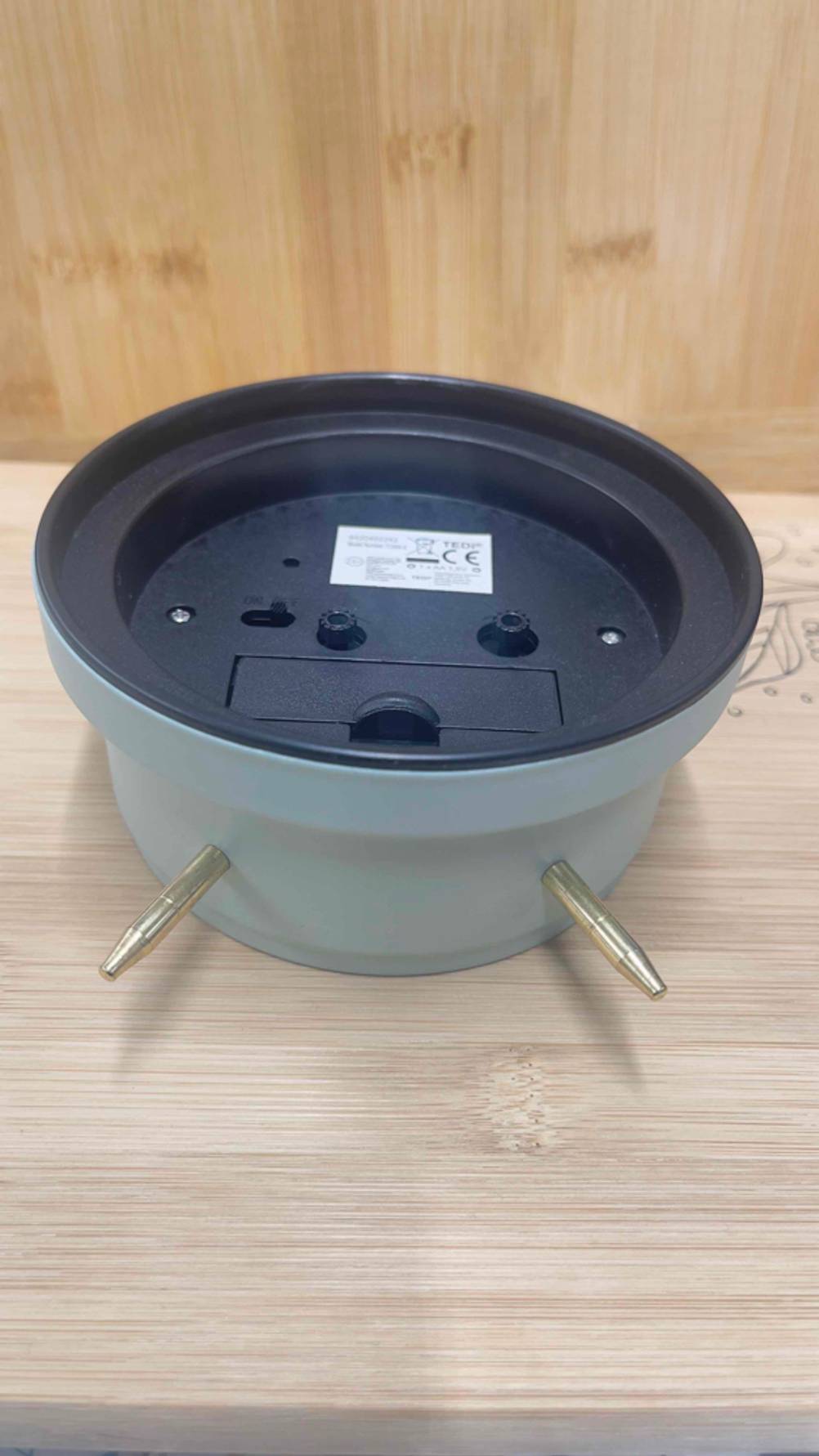 Der Analog-Wecker im Test mit der Rückseite nach oben auf einer Holzfläche liegend.