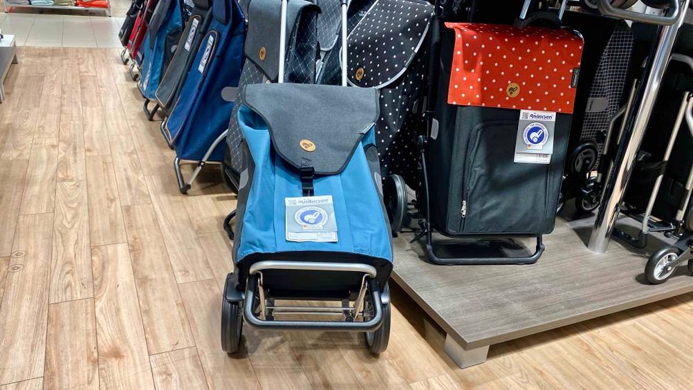 Getestet: Ein Einkaufstrolley von schräg unten mit Fokus auf den Boden, im Hintergrund andere Trolleys auf einem Sockel.