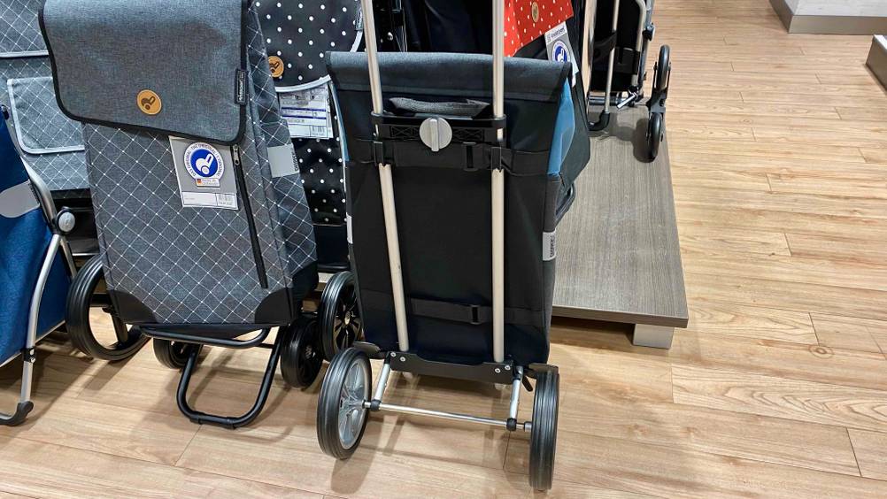 Ein Einkaufstrolley im Test von hinten neben anderen Produkten in einer Verkaufsfläche stehend.