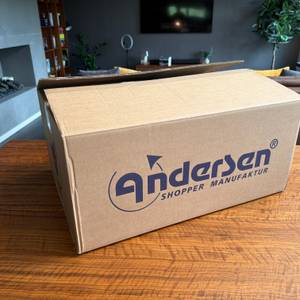 Der Karton des Andersen Scala Shopper Hera steht auf einem Tisch.