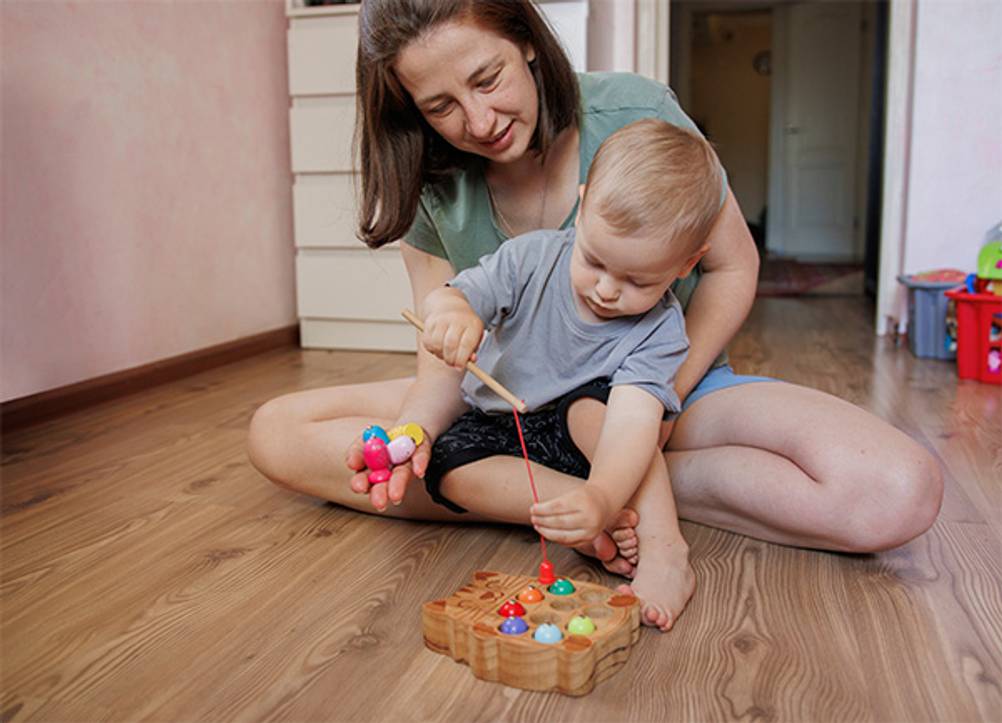 Angelspiel im Test: Eine Mutter mit Sohn vor einem hölzernen Angelspiel