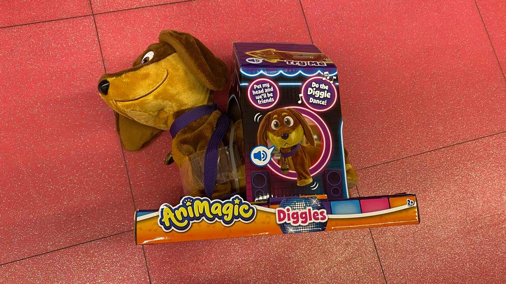 Ein AniMagic Spielzeug-Hund im Test, der läuft und bellt in seiner Verpackung auf rotem Untergrund, mit Sicht auf die braune Plüschverarbeitung inklusive langer Ohren.