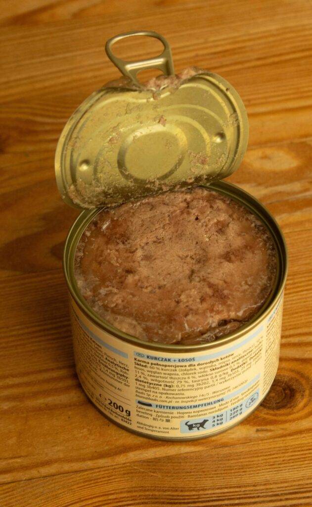Ein getreidefreies Nassfutter für Katzen im Test steht in einer geöffneten 200-g-Dose auf einer Holzfläche.