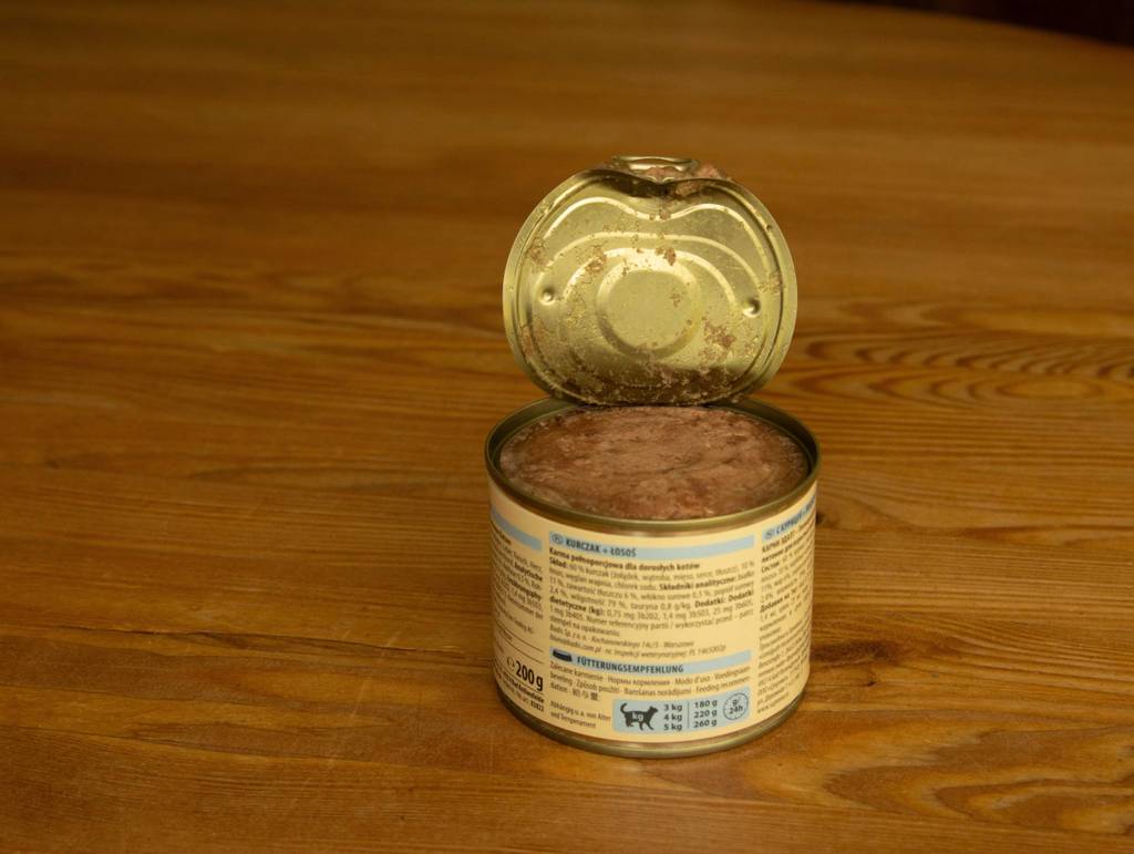 Ein getreidefreies Nassfutter für Katzen im Test befindet sich in einer geöffneten 200-g-Dose auf einer Holzfläche.