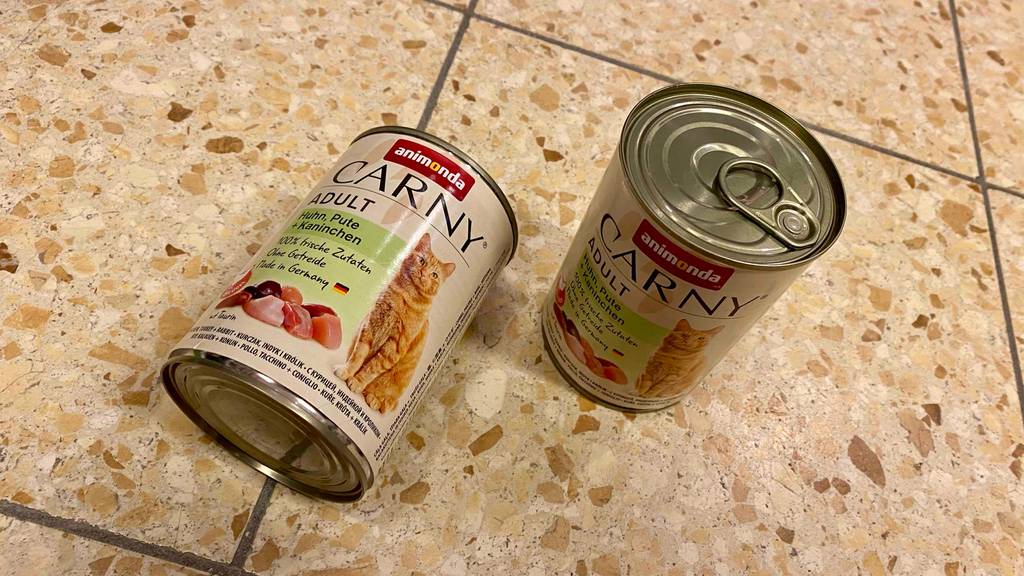 Katzenfutter mit hohem Fleischanteil im Test: eine Dose steht neben einer liegenden auf einem Fliesenboden.