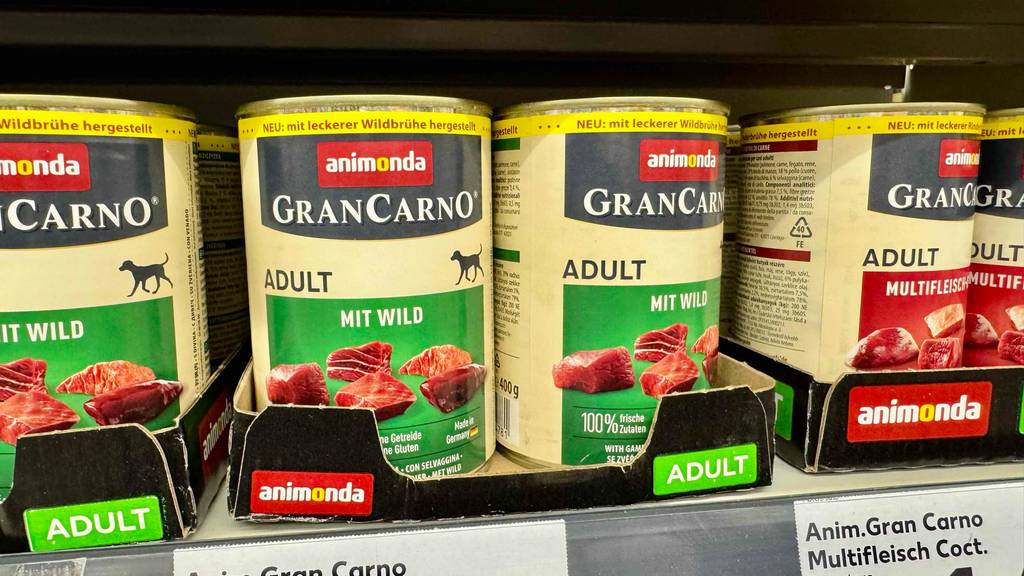 Getestetes Hunderfutter mit hohem Fleischanteil in Dosen steht nebeneinander in einem Verkaufsregal.