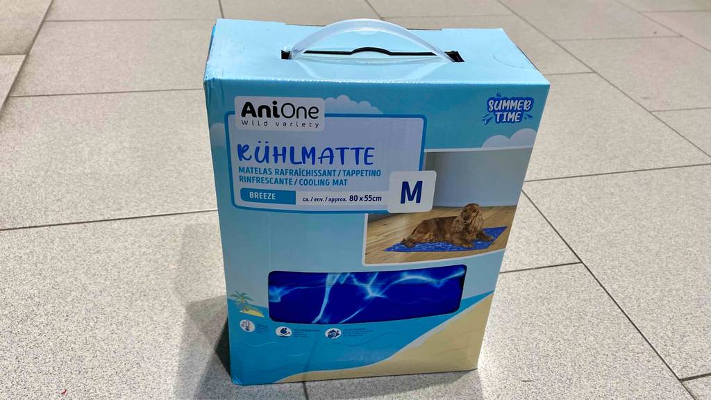 Kühlmatten für Hunde im Test: Eine Kühlmatte in Größe M von Anione steht in ihrer hellblauen Verpackung auf einem Fliesenboden.