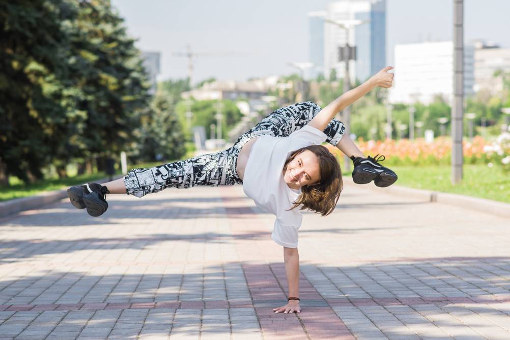Anker-Bluetooth-Lautsprecher im Test: Junge Frau tanzt Breakdance auf einer gepflasterten Straße vor einer urbanen Skyline.