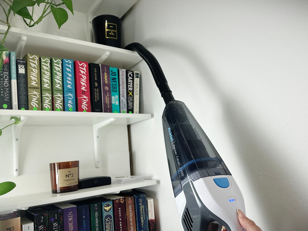 Der Anktel 601-N mit angeschlossenem flexiblem Verlängerungsschlauch saugt oberhalb eines Bücherregals.