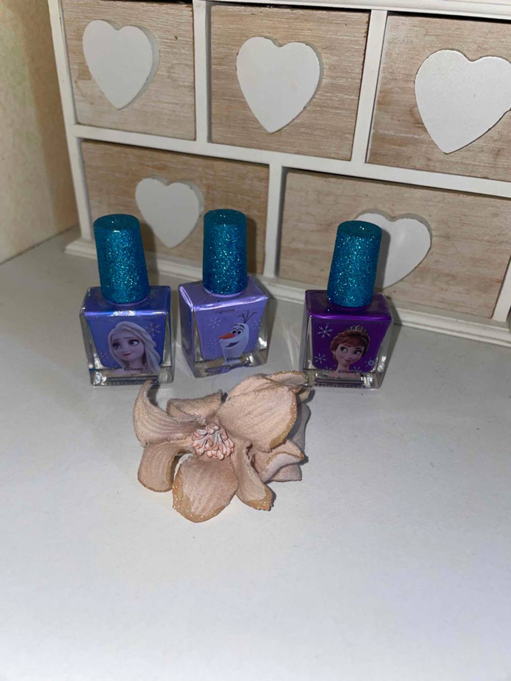 Drei verschiedenfarbige Kinder-Nagellacke im Test stehen nebeneinander auf dem Boden.