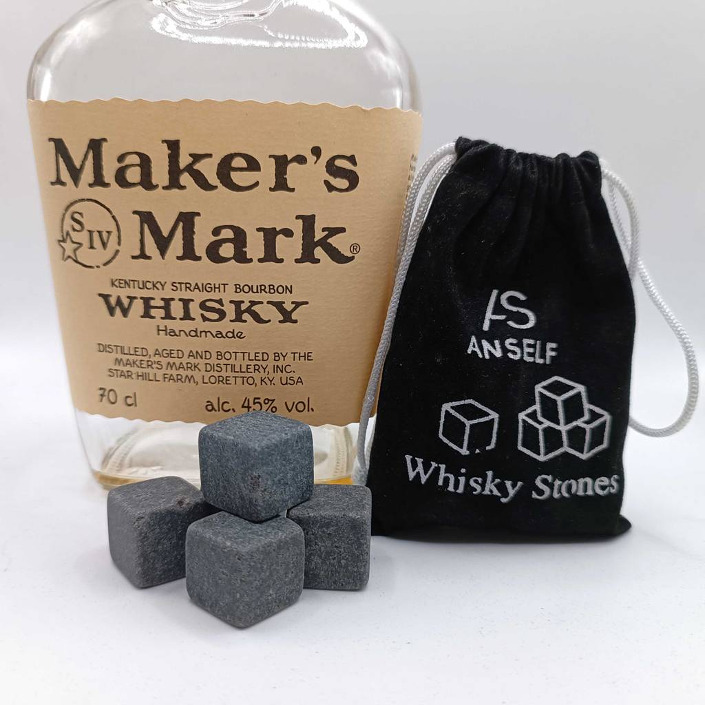 Graue Whisky-Steine im Test liegen vor einer Flasche Whisky und ihrem Aufbewahrungssäckchen.